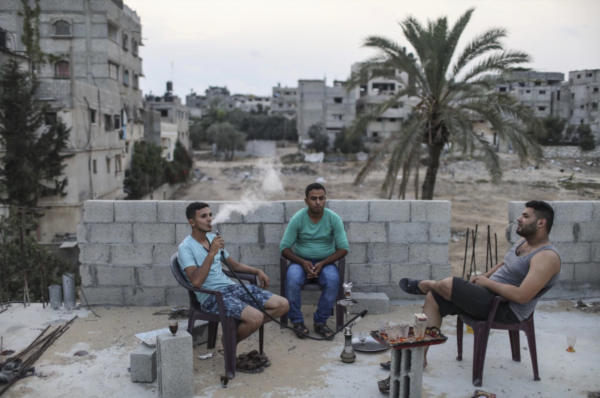 Ahmed Abu Duhair, 25, left, smokes with Mahmoud al-Sweasi, center, and Iyad Abu Heweila, 24, on a roof in Gaza City. (Wissam Nassar/for The Washington Post)